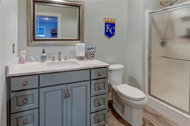 bathroom featuring vanity, wood-type flooring, an enclosed shower, and toilet