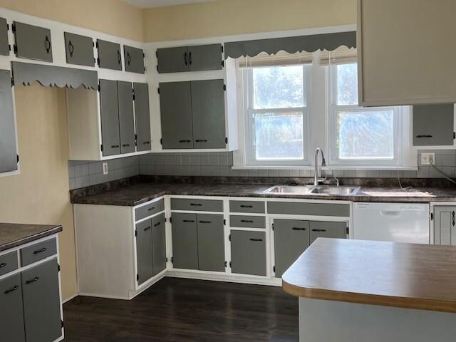 kitchen with dark hardwood / wood-style flooring, tasteful backsplash, white dishwasher, sink, and gray cabinets