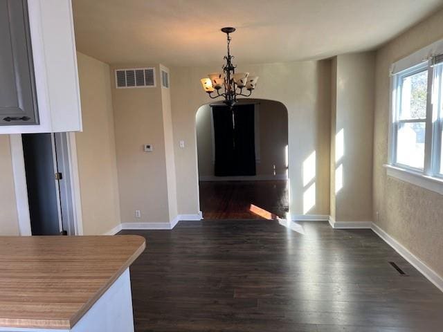 unfurnished dining area with dark hardwood / wood-style flooring and an inviting chandelier