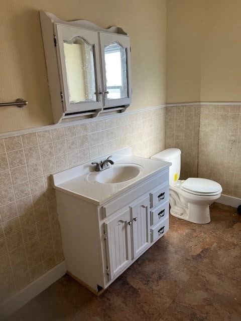 bathroom with vanity, toilet, and tile walls