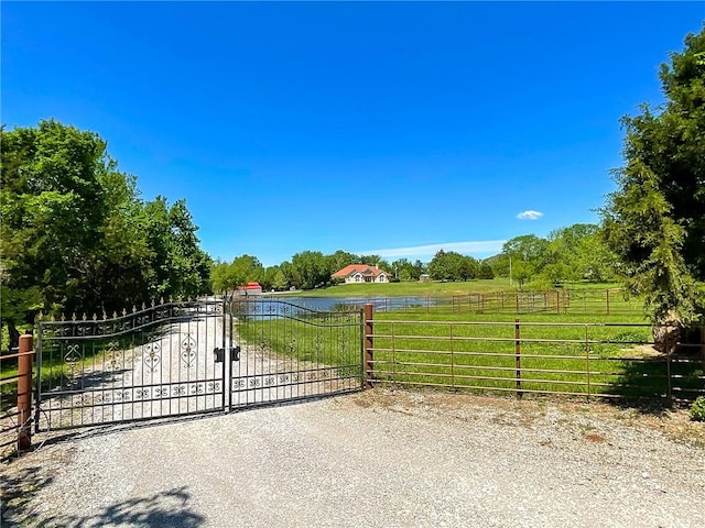 view of gate with a yard and a rural view