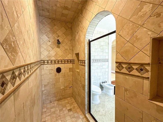 bathroom featuring toilet, a bidet, tile walls, and tiled shower