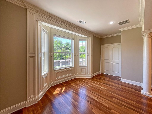 interior space featuring decorative columns, wood-type flooring, and ornamental molding