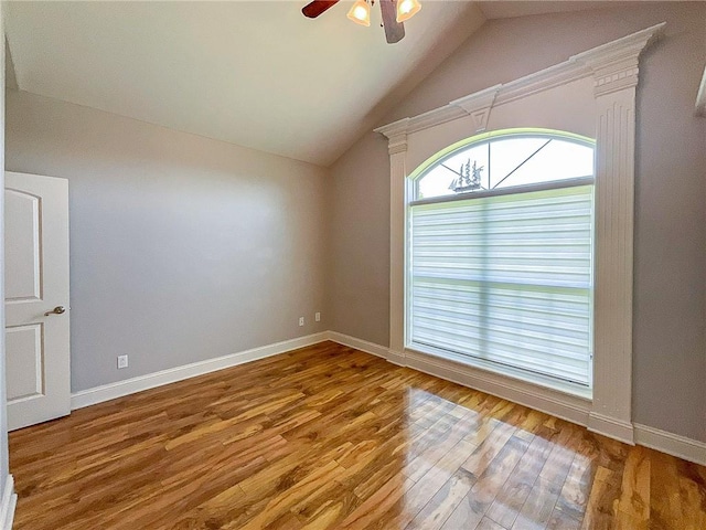 empty room with ceiling fan, hardwood / wood-style floors, and lofted ceiling