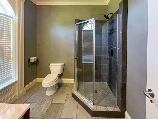 bathroom featuring an enclosed shower, vanity, toilet, and crown molding