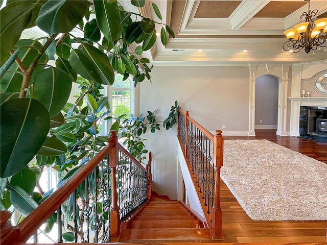 staircase featuring hardwood / wood-style floors, ornamental molding, and an inviting chandelier