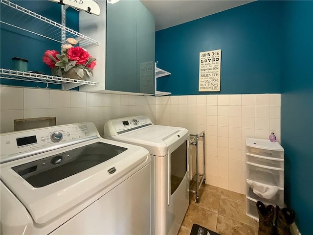 laundry room with light tile patterned flooring, independent washer and dryer, and tile walls