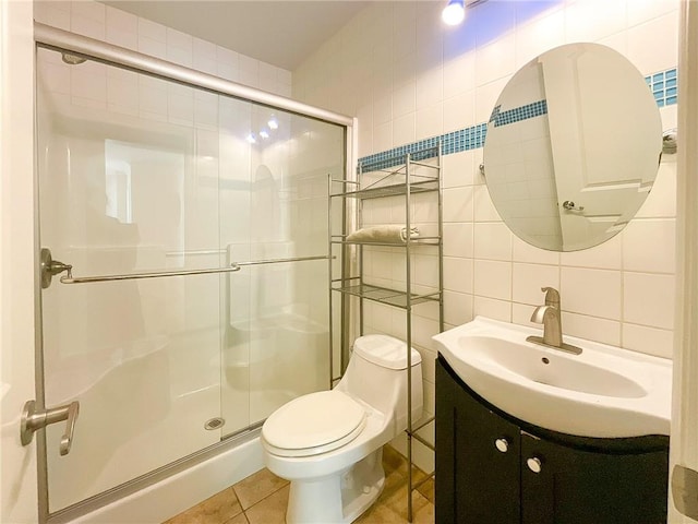 bathroom featuring tasteful backsplash, tile walls, tile patterned flooring, toilet, and a shower with shower door