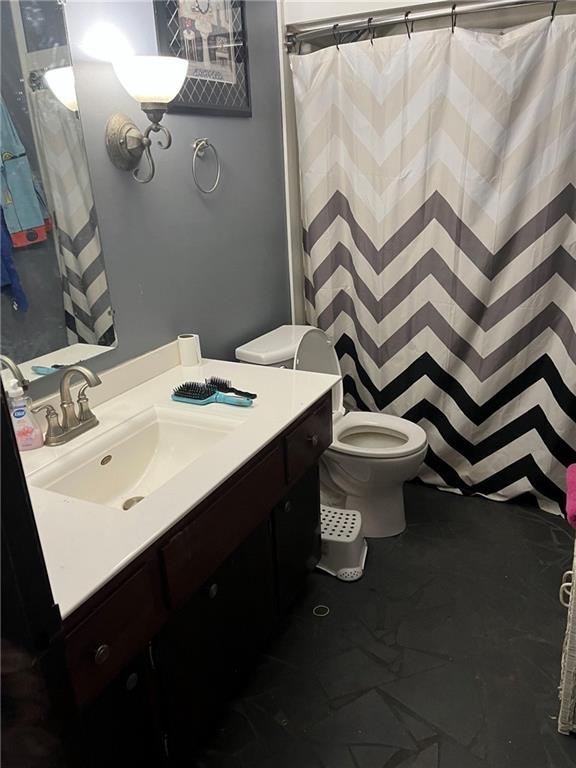 bathroom with a shower with shower curtain, vanity, and toilet