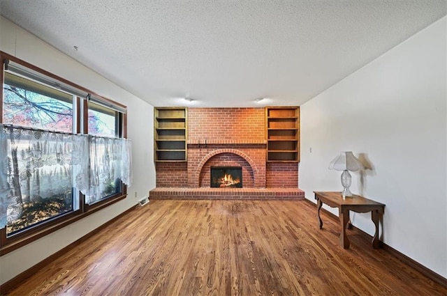 living room with a textured ceiling, wood-type flooring, and a fireplace