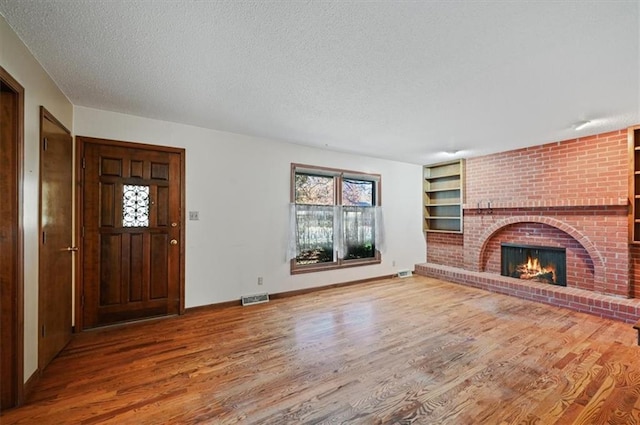 unfurnished living room featuring hardwood / wood-style floors, a fireplace, and a textured ceiling