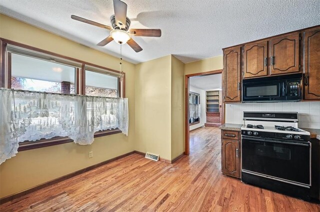 kitchen featuring a textured ceiling, light wood-type flooring, tasteful backsplash, and range with gas stovetop