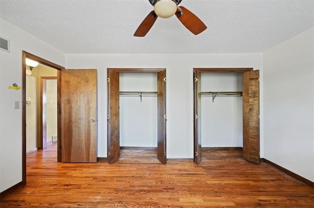 unfurnished bedroom featuring a textured ceiling, two closets, light hardwood / wood-style flooring, and ceiling fan