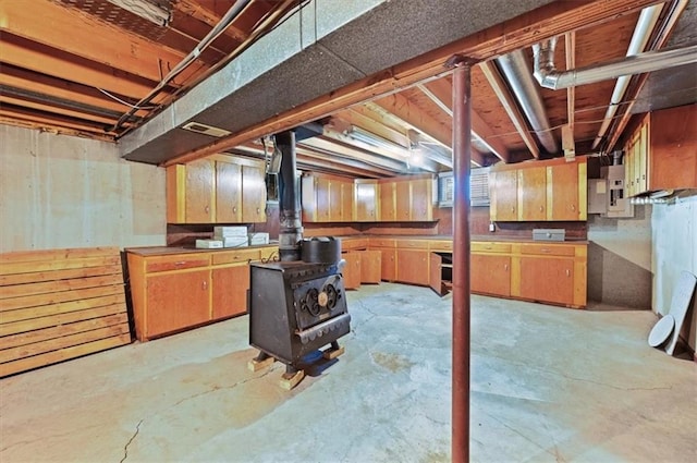 basement with a wood stove and electric panel