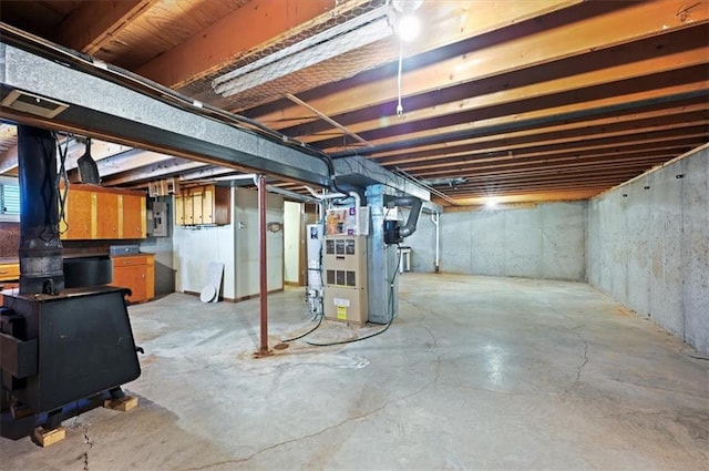 basement featuring heating unit, water heater, and electric panel