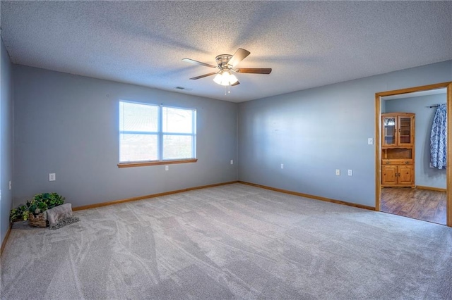 spare room featuring a textured ceiling, light colored carpet, and ceiling fan