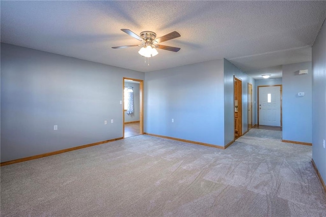 empty room with ceiling fan, light colored carpet, and a textured ceiling