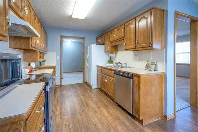 kitchen featuring hardwood / wood-style flooring, sink, stainless steel appliances, and a textured ceiling