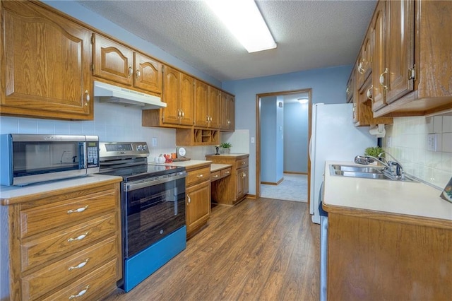 kitchen with sink, stainless steel appliances, hardwood / wood-style floors, a textured ceiling, and decorative backsplash