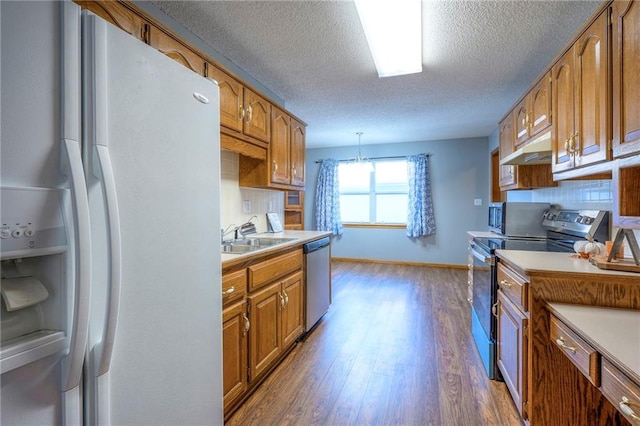 kitchen featuring sink, hanging light fixtures, dark hardwood / wood-style floors, decorative backsplash, and stainless steel appliances