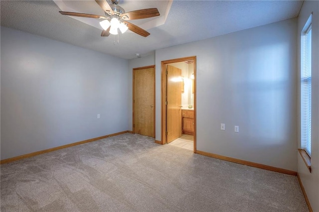 unfurnished bedroom with a textured ceiling, ceiling fan, light carpet, and connected bathroom