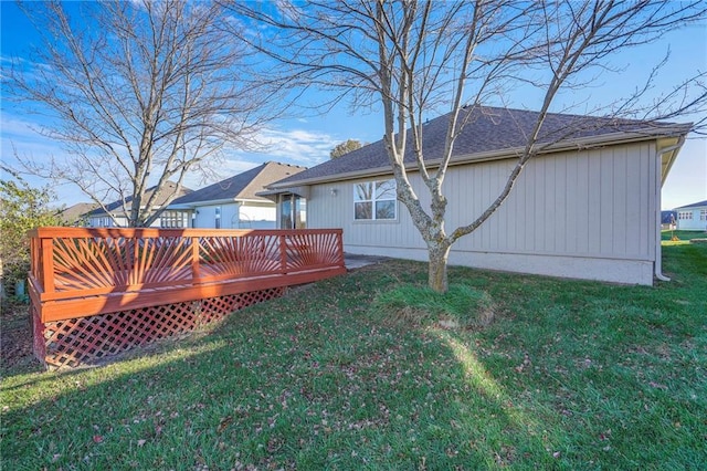 rear view of property featuring a lawn and a deck