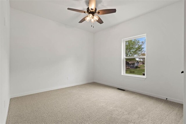 unfurnished room featuring baseboards, a ceiling fan, visible vents, and light colored carpet