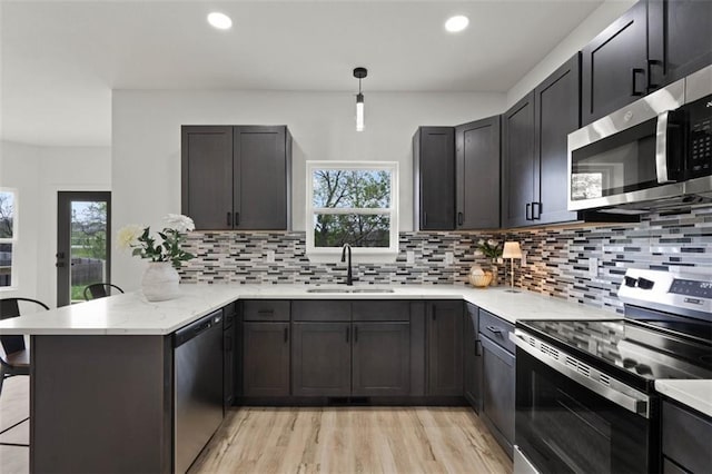 kitchen featuring a peninsula, a wealth of natural light, appliances with stainless steel finishes, and a sink
