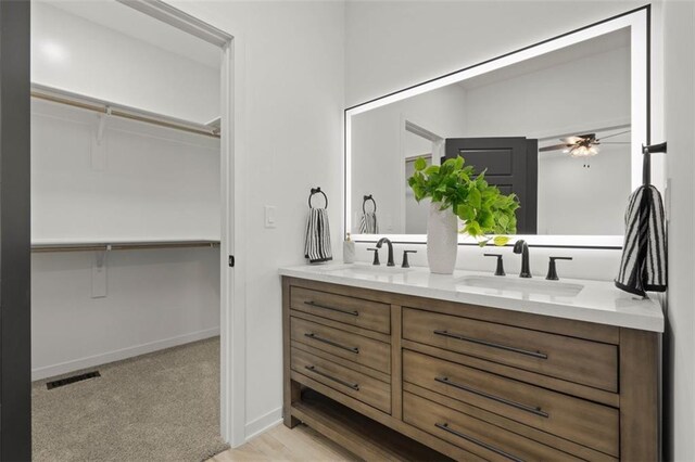 bathroom with a spacious closet, ceiling fan, a sink, and double vanity
