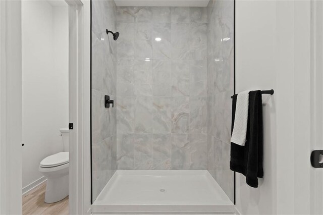 bathroom featuring a shower stall, toilet, and wood finished floors