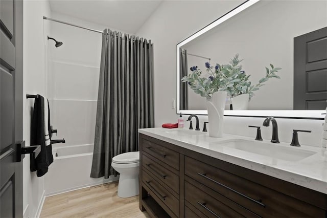 bathroom featuring a sink, double vanity, toilet, shower / tub combo, and wood finished floors