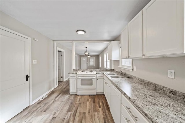 kitchen with kitchen peninsula, white appliances, sink, white cabinets, and light hardwood / wood-style floors