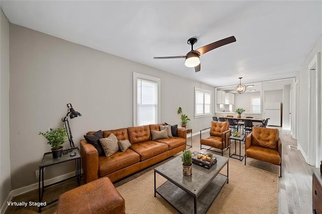 living room featuring light hardwood / wood-style flooring and ceiling fan with notable chandelier