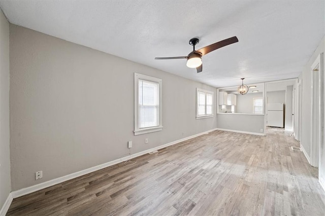 spare room featuring ceiling fan with notable chandelier and wood-type flooring