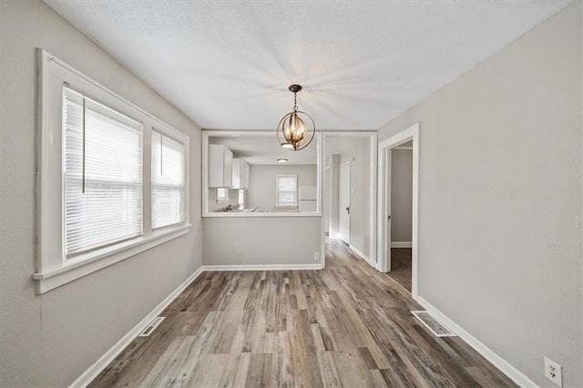 unfurnished dining area with hardwood / wood-style floors and an inviting chandelier