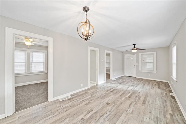 interior space featuring ceiling fan with notable chandelier and light hardwood / wood-style flooring