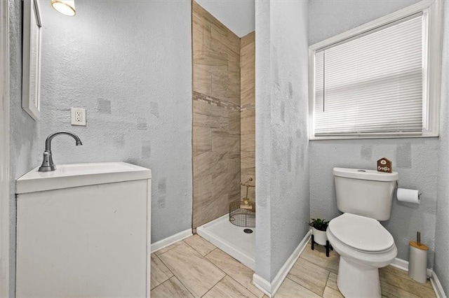 bathroom featuring a tile shower, sink, and toilet