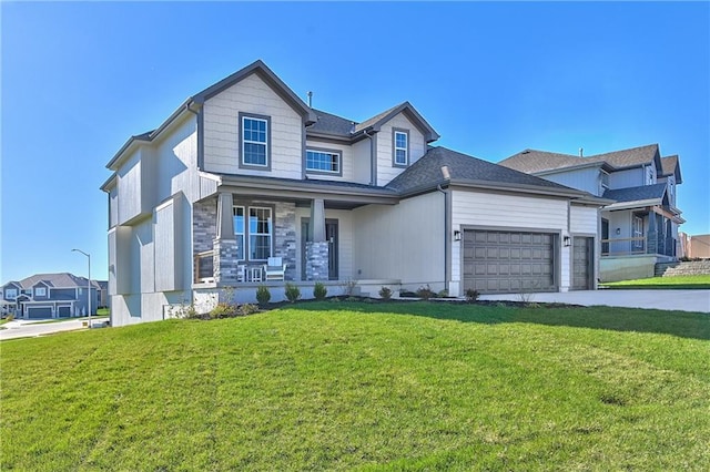 view of front of home featuring covered porch, a garage, and a front lawn