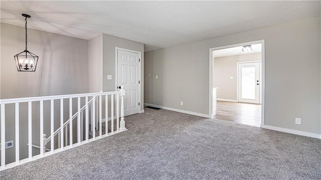 unfurnished room featuring carpet flooring, a notable chandelier, and a textured ceiling