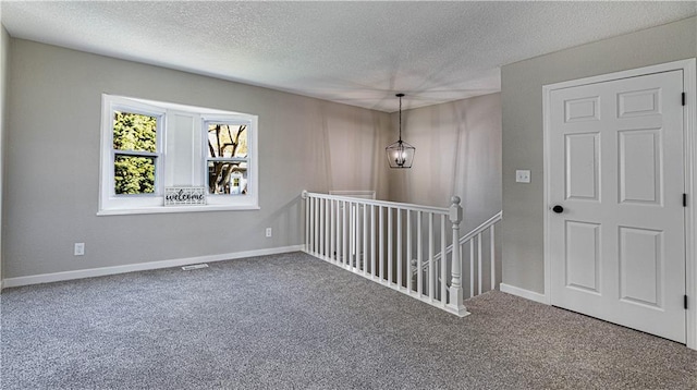 empty room featuring carpet floors, an inviting chandelier, and a textured ceiling