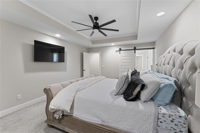 carpeted bedroom featuring a raised ceiling, a barn door, and ceiling fan