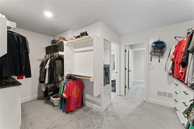 walk in closet with light colored carpet