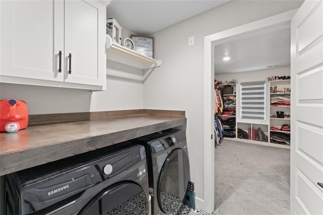 clothes washing area featuring cabinets, washing machine and dryer, and light carpet