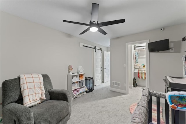 bedroom featuring carpet, a barn door, ceiling fan, and a walk in closet