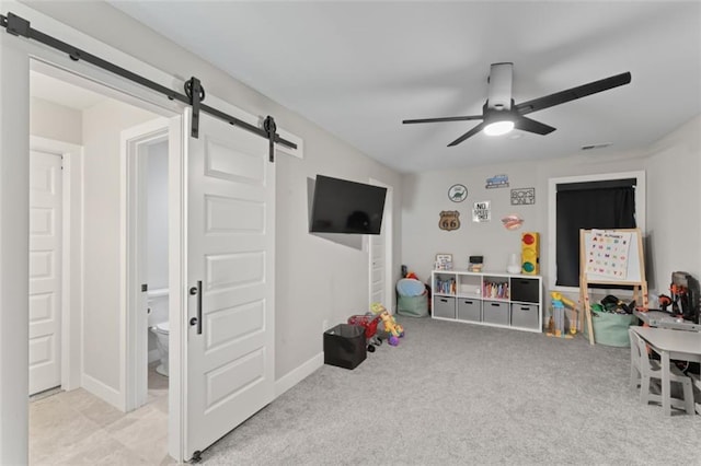 rec room with a barn door, light colored carpet, and ceiling fan