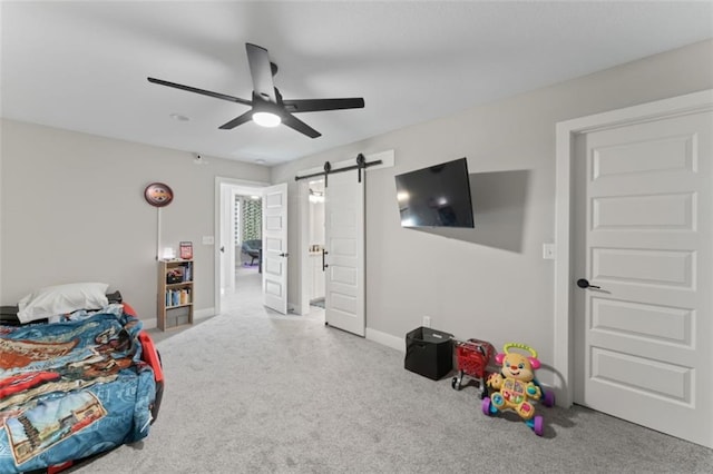 carpeted bedroom with a barn door and ceiling fan