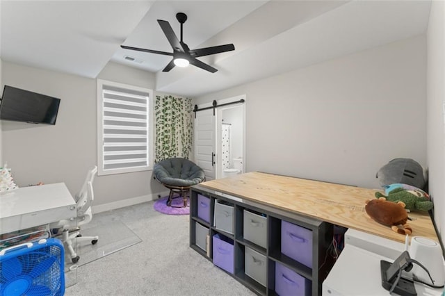 carpeted office space featuring ceiling fan and a barn door