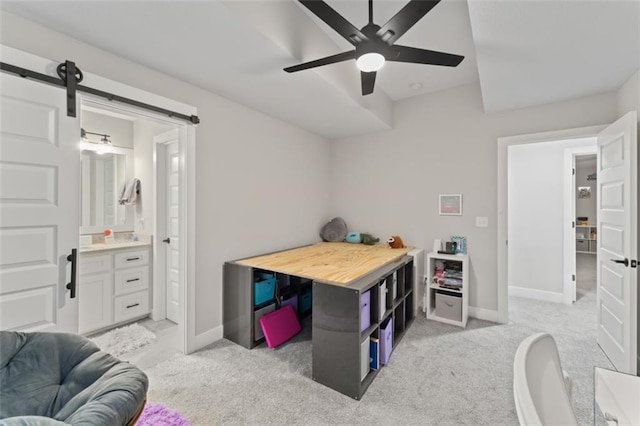 bedroom featuring light carpet, a barn door, ensuite bath, and ceiling fan