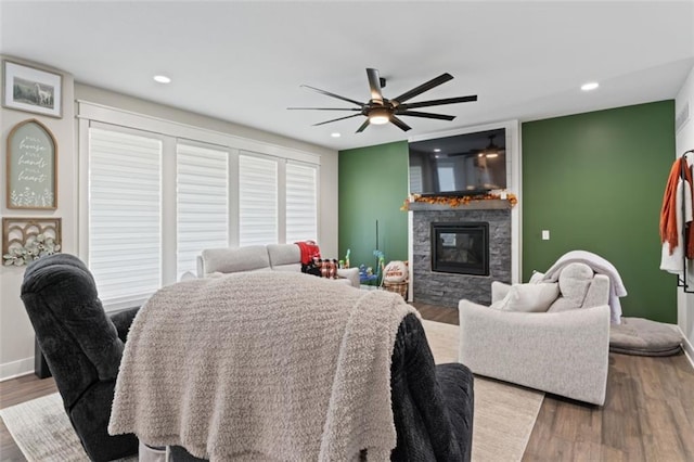 living room with a fireplace, ceiling fan, and dark wood-type flooring