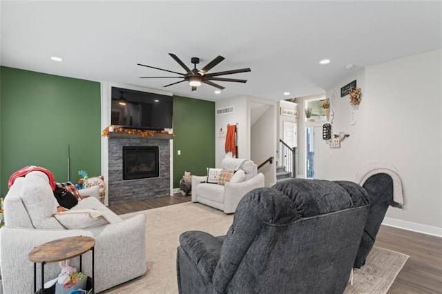 living room with hardwood / wood-style floors, a stone fireplace, and ceiling fan